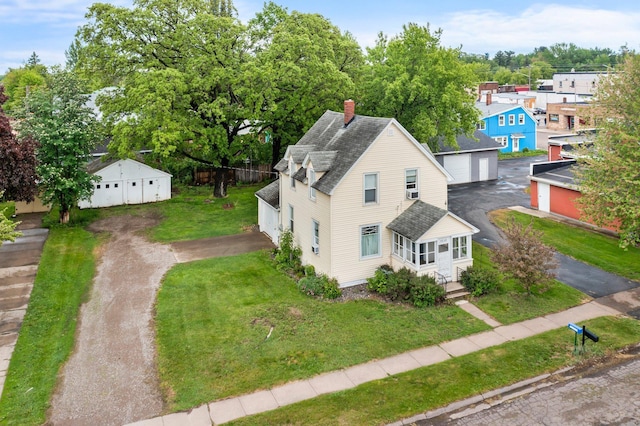 208 2nd St SW, Braham, MN 55006 - view of front of house with a shingled roof, a front yard, a chimney, a garage, and an outdoor structure