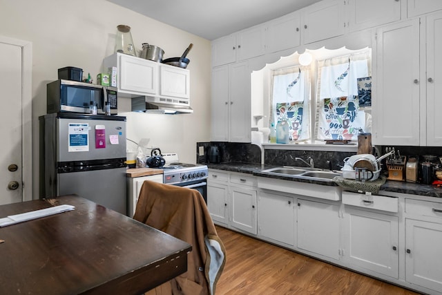 208 2nd St SW, Braham, MN 55006 - kitchen featuring stainless steel appliances, dark countertops, a sink, and white cabinetry