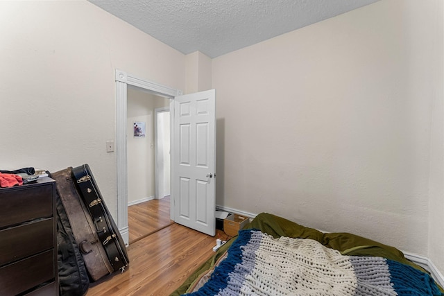 208 2nd St SW, Braham, MN 55006 - bedroom with light wood finished floors, baseboards, and a textured ceiling