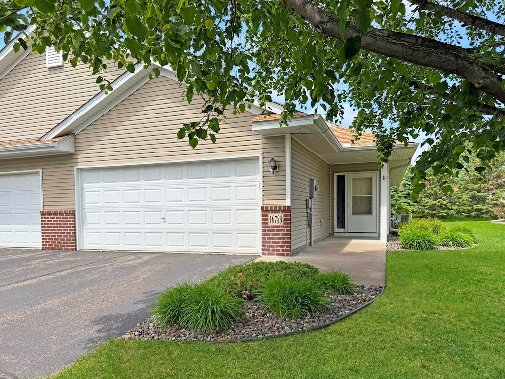 10783 Tyler Ct NE, Blaine, MN 55434 - view of front of home featuring brick siding, driveway, an attached garage, and a front yard