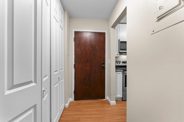 179 Little Canada Rd E Unit 230, Little Canada, MN 55117 - hallway with light wood-style flooring, a textured ceiling, and baseboards