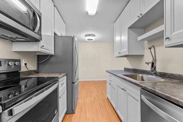 179 Little Canada Rd E Unit 230, Little Canada, MN 55117 - kitchen featuring appliances with stainless steel finishes, a sink, light wood-style flooring, baseboards, and a textured ceiling