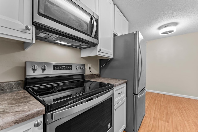 179 Little Canada Rd E Unit 230, Little Canada, MN 55117 - kitchen featuring appliances with stainless steel finishes, white cabinets, light wood-style floors, baseboards, and a textured ceiling