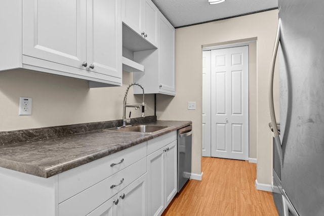 179 Little Canada Rd E Unit 230, Little Canada, MN 55117 - kitchen featuring appliances with stainless steel finishes, a sink, dark countertops, light wood finished floors, and white cabinetry