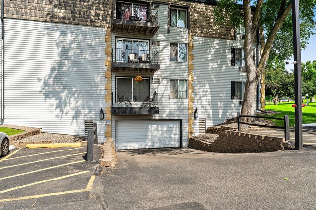 179 Little Canada Rd E Unit 230, Little Canada, MN 55117 - view of property exterior with mansard roof, an attached garage, and a balcony