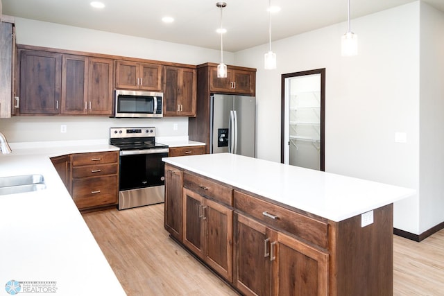 405 16th St NE, Dilworth, MN 56529 - kitchen with appliances with stainless steel finishes, a sink, light wood-type flooring, light countertops, and pendant lighting