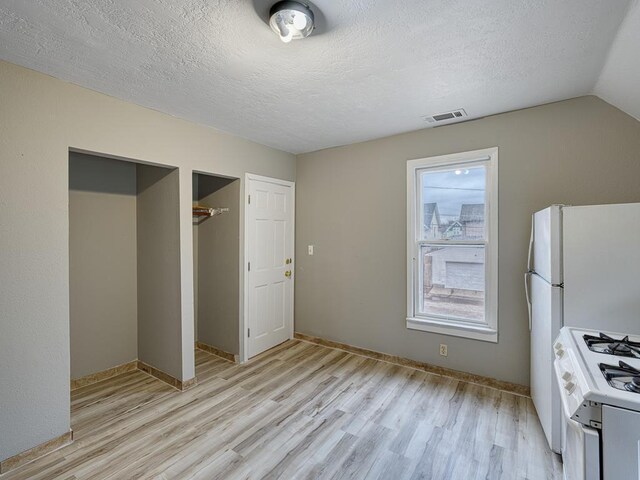 818 Edmund Ave, Saint Paul, MN 55104 - unfurnished bedroom featuring light wood-type flooring, a textured ceiling, baseboards, a closet, and vaulted ceiling