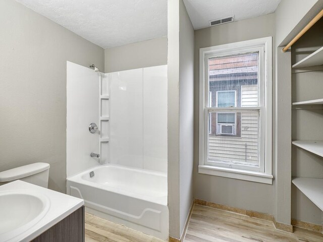 818 Edmund Ave, Saint Paul, MN 55104 - bathroom featuring wood finished floors, bathing tub / shower combination, a textured ceiling, baseboards, and vanity