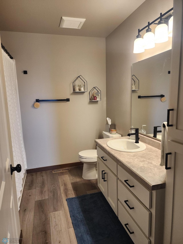 1743 46th Ave S, Moorhead, MN 56560 - full bathroom featuring toilet, vanity, wood finished floors, and baseboards
