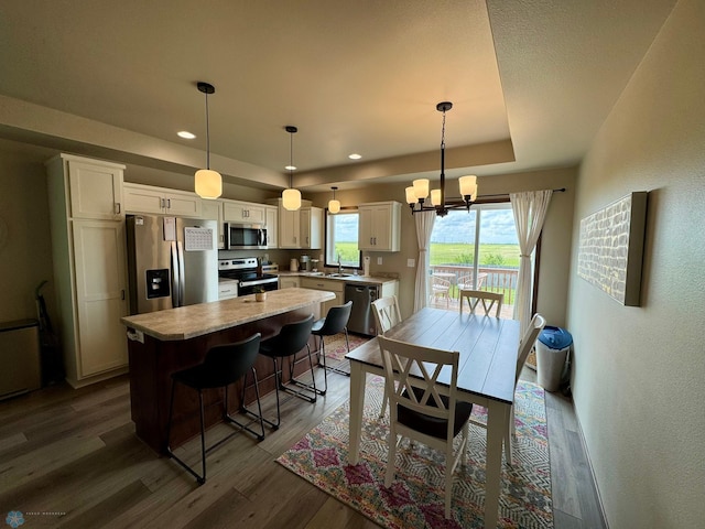 1743 46th Ave S, Moorhead, MN 56560 - kitchen with appliances with stainless steel finishes, dark wood-style flooring, white cabinets, a center island, and a chandelier