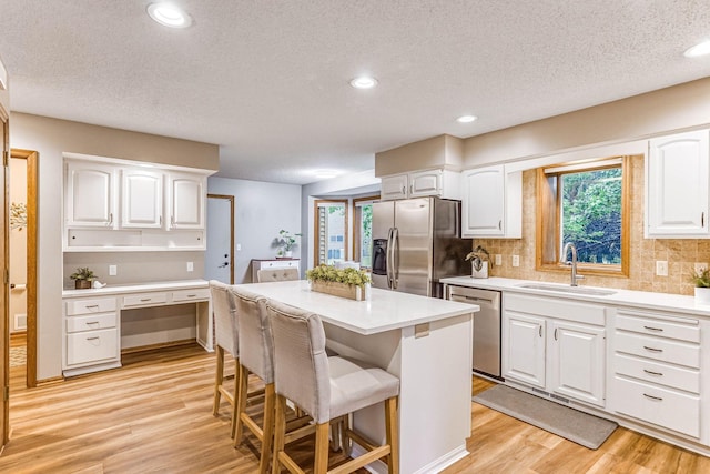 38 Jefferson Ct, Hastings, MN 55033 - kitchen with appliances with stainless steel finishes, a sink, light wood-style flooring, white cabinetry, and a kitchen island