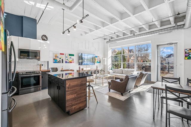 111 Franklin Ave Unit 105, Minneapolis, MN 55404 - kitchen featuring appliances with stainless steel finishes, a center island, backsplash, a towering ceiling, and finished concrete flooring