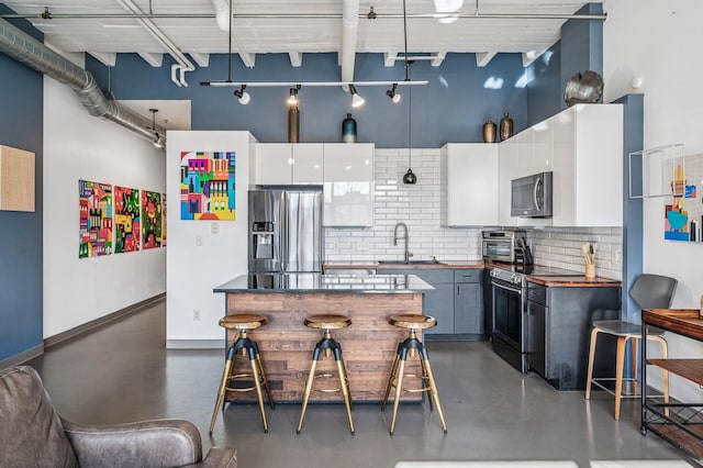 111 Franklin Ave Unit 105, Minneapolis, MN 55404 - kitchen with appliances with stainless steel finishes, finished concrete flooring, tasteful backsplash, wood counters, and white cabinetry