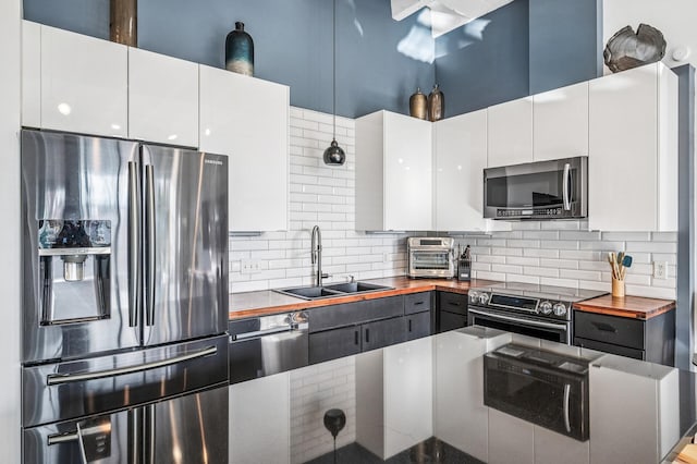 111 Franklin Ave Unit 105, Minneapolis, MN 55404 - kitchen with appliances with stainless steel finishes, a sink, decorative backsplash, and white cabinets
