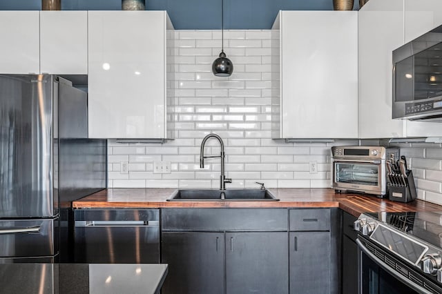 111 Franklin Ave Unit 105, Minneapolis, MN 55404 - kitchen with wood counters, a sink, appliances with stainless steel finishes, and decorative backsplash