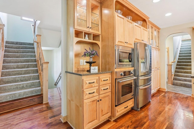 15758 Austin St NE, Ham Lake, MN 55304 - kitchen with appliances with stainless steel finishes, open shelves, wood finished floors, glass insert cabinets, and dark stone counters