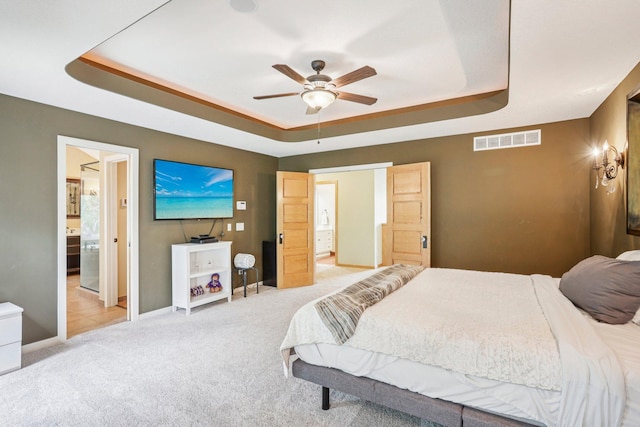 15758 Austin St NE, Ham Lake, MN 55304 - bedroom with a tray ceiling, light carpet, connected bathroom, and a ceiling fan
