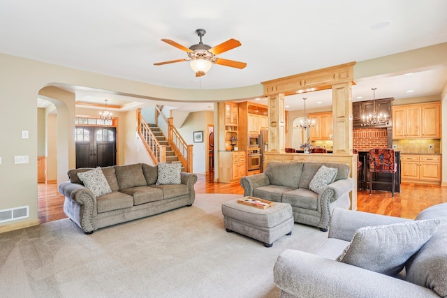 15758 Austin St NE, Ham Lake, MN 55304 - living area with arched walkways, a chandelier, a ceiling fan, light wood-style flooring, and stairway