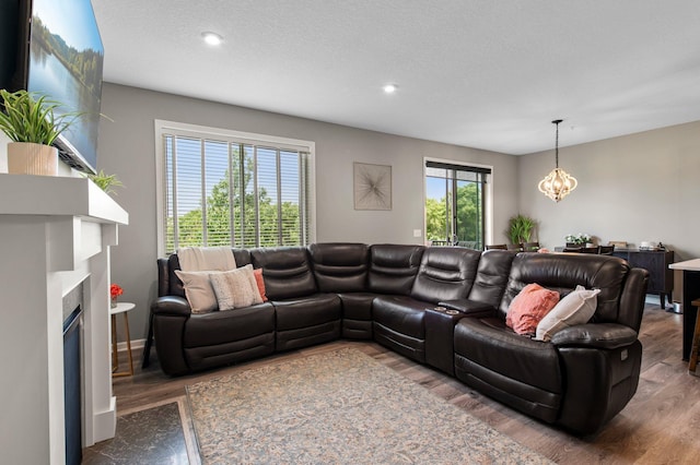 14834 Willemite Way NW, Ramsey, MN 55303 - living room with wood finished floors, a chandelier, recessed lighting, a fireplace with flush hearth, and a textured ceiling