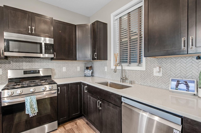 14834 Willemite Way NW, Ramsey, MN 55303 - kitchen featuring stainless steel appliances, a sink, light countertops, dark brown cabinetry, and decorative backsplash