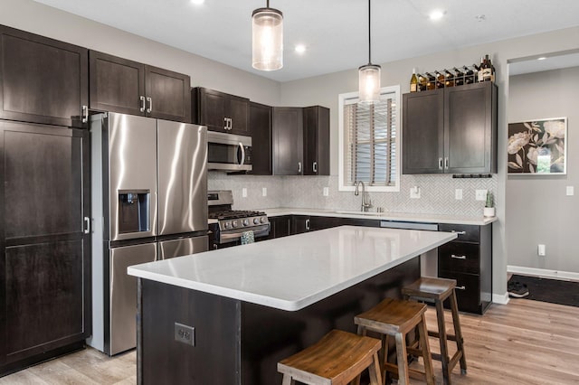 14834 Willemite Way NW, Ramsey, MN 55303 - kitchen with appliances with stainless steel finishes, a sink, a breakfast bar area, tasteful backsplash, and light wood-type flooring
