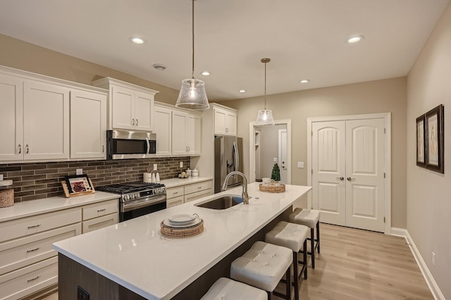 5054 Dale Ridge Rd, Woodbury, MN 55129 - kitchen with stainless steel appliances, a sink, decorative backsplash, a breakfast bar, and an island with sink