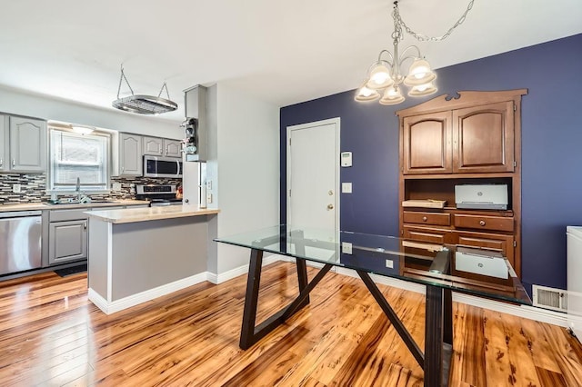 7724 Major Ave N, Brooklyn Park, MN 55443 - kitchen featuring stainless steel appliances, a sink, light countertops, light wood finished floors, and backsplash