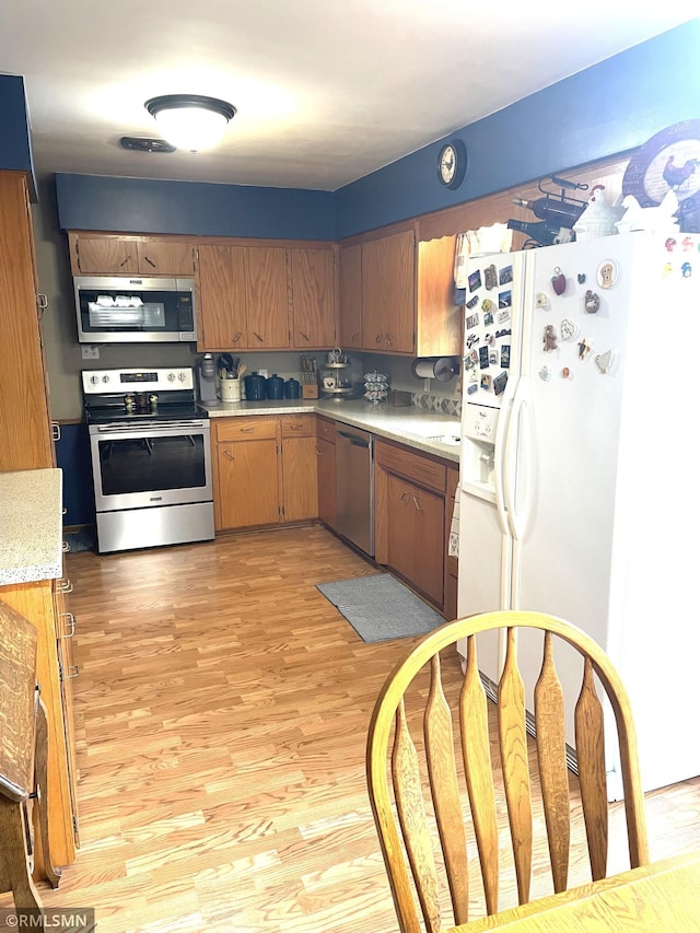 705 Turril St, Le Sueur, MN 56058 - kitchen with stainless steel appliances, light countertops, light wood-type flooring, and brown cabinets