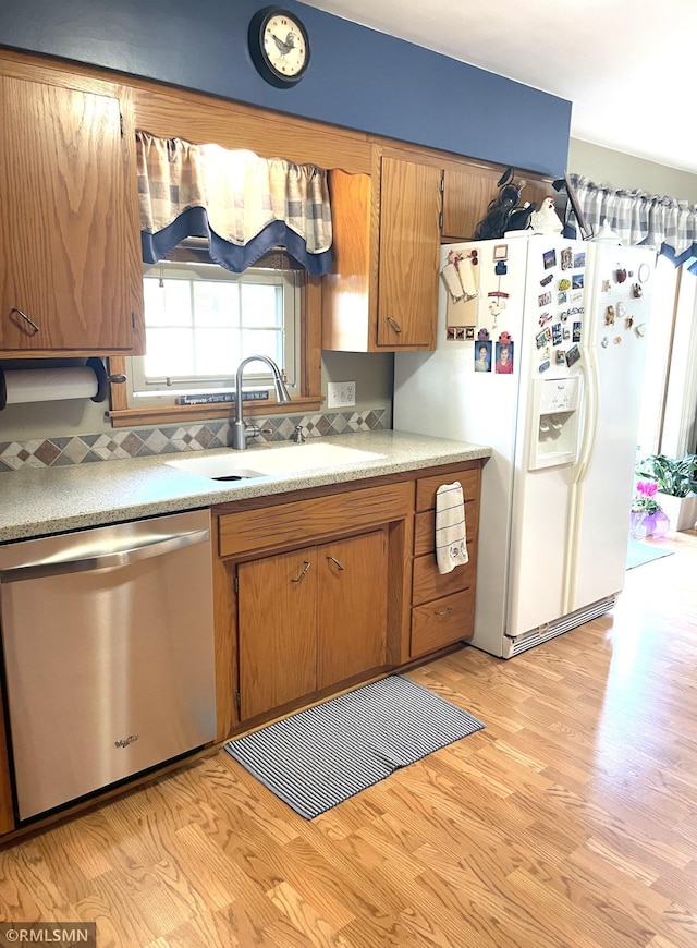 705 Turril St, Le Sueur, MN 56058 - kitchen featuring dishwasher, white fridge with ice dispenser, a sink, light wood finished floors, and brown cabinets