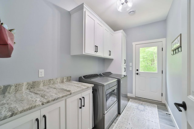 16460 Sanctuary Way, Brainerd, MN 56401 - laundry area with washing machine and clothes dryer, cabinet space, baseboards, and light wood-style flooring