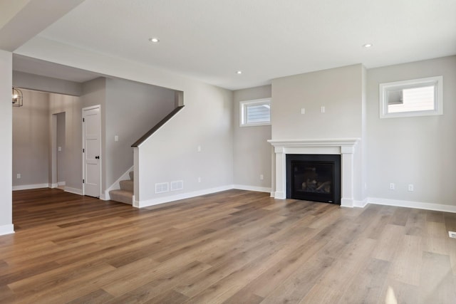 6135 Harkness Ln S, Cottage Grove, MN 55016 - unfurnished living room with wood finished floors, stairway, a glass covered fireplace, and recessed lighting