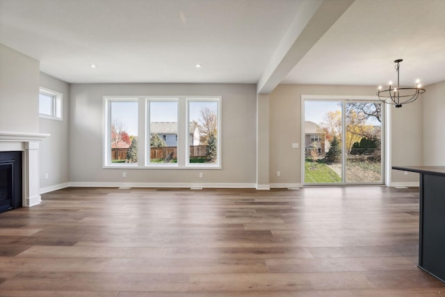 6135 Harkness Ln S, Cottage Grove, MN 55016 - unfurnished living room featuring a chandelier, wood finished floors, a glass covered fireplace, recessed lighting, and beam ceiling