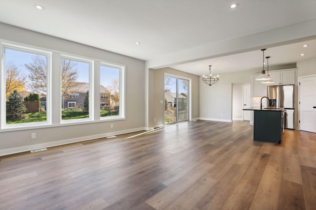 6135 Harkness Ln S, Cottage Grove, MN 55016 - unfurnished living room with a chandelier, plenty of natural light, recessed lighting, and dark wood-style flooring