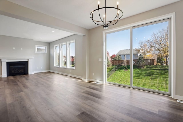 6135 Harkness Ln S, Cottage Grove, MN 55016 - unfurnished living room with a chandelier, wood finished floors, a glass covered fireplace, and recessed lighting