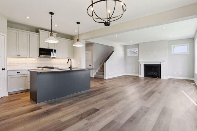 6135 Harkness Ln S, Cottage Grove, MN 55016 - kitchen featuring tasteful backsplash, a kitchen island with sink, recessed lighting, light wood finished floors, and hanging light fixtures