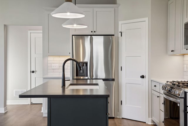 6135 Harkness Ln S, Cottage Grove, MN 55016 - kitchen with appliances with stainless steel finishes, tasteful backsplash, wood finished floors, and a kitchen island with sink