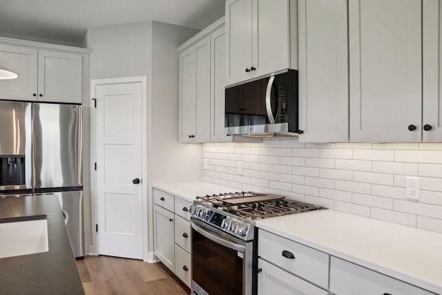 6135 Harkness Ln S, Cottage Grove, MN 55016 - kitchen with stainless steel appliances, light wood-style floors, tasteful backsplash, and light countertops