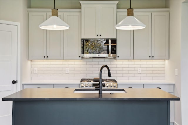 6135 Harkness Ln S, Cottage Grove, MN 55016 - kitchen featuring stainless steel microwave, decorative backsplash, pendant lighting, and a center island with sink
