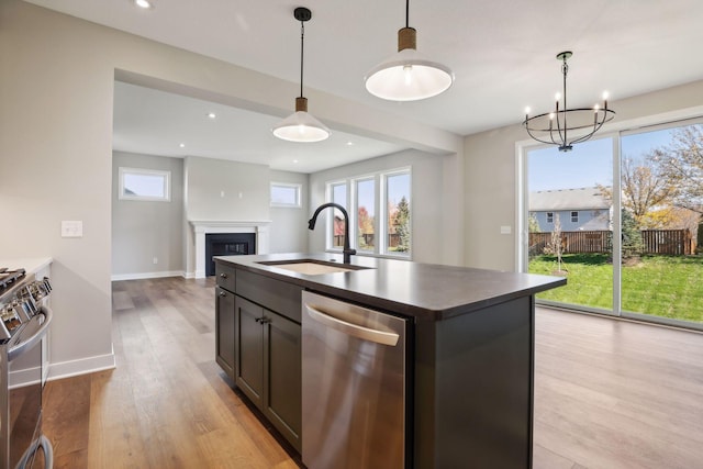 6135 Harkness Ln S, Cottage Grove, MN 55016 - kitchen with stainless steel appliances, dark countertops, light wood-type flooring, a chandelier, and a glass covered fireplace