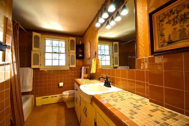 2645 Riverside Ln NE, Rochester, MN 55906 - full bathroom featuring baseboard heating, healthy amount of natural light, vanity, toilet, and tile walls