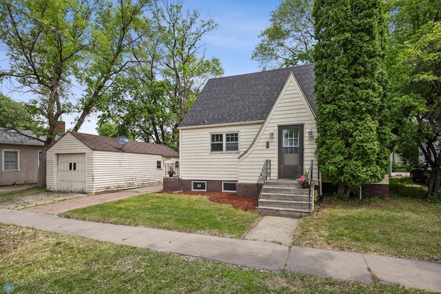 310 10th St S, Moorhead, MN 56560 - a-frame home featuring a garage, an outdoor structure, a front lawn, roof with shingles, and driveway