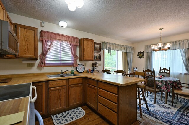 27681 Moser Dr, Jackson Twp, WI 54893 - kitchen with a sink, a peninsula, a textured ceiling, a chandelier, and brown cabinetry