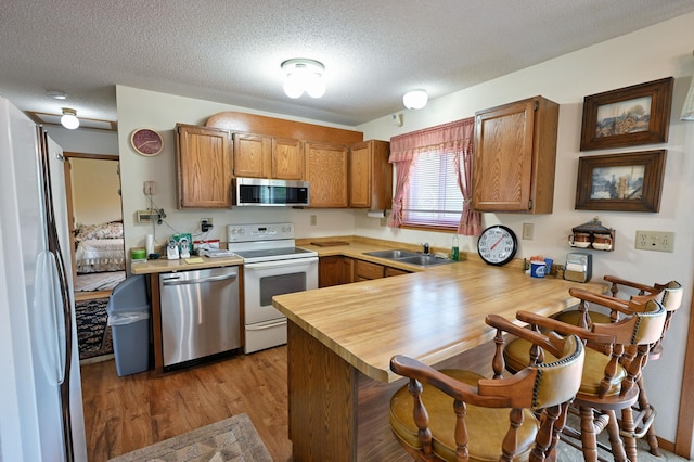 27681 Moser Dr, Jackson Twp, WI 54893 - kitchen featuring appliances with stainless steel finishes, a sink, a peninsula, a kitchen bar, and light wood-style floors