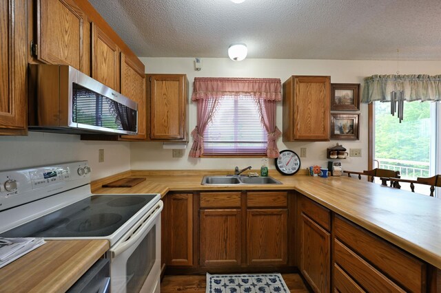 27681 Moser Dr, Jackson Twp, WI 54893 - kitchen with white range with electric stovetop, stainless steel microwave, a sink, light countertops, and a textured ceiling