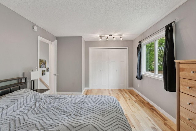 265 107th Ln NW, Coon Rapids, MN 55448 - bedroom with light wood-style floors, a textured ceiling, a closet, and baseboards