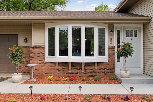 265 107th Ln NW, Coon Rapids, MN 55448 - view of exterior entry with a garage, brick siding, and a shingled roof