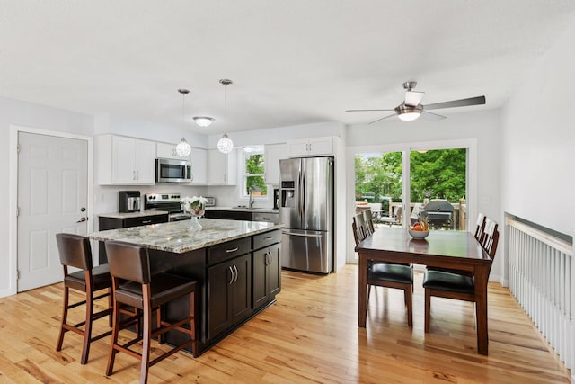 265 107th Ln NW, Coon Rapids, MN 55448 - kitchen with appliances with stainless steel finishes, light wood-style flooring, a sink, a kitchen island, and a ceiling fan
