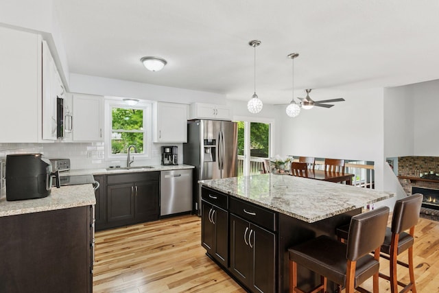 265 107th Ln NW, Coon Rapids, MN 55448 - kitchen with stainless steel appliances, a sink, a kitchen bar, ceiling fan, and tasteful backsplash