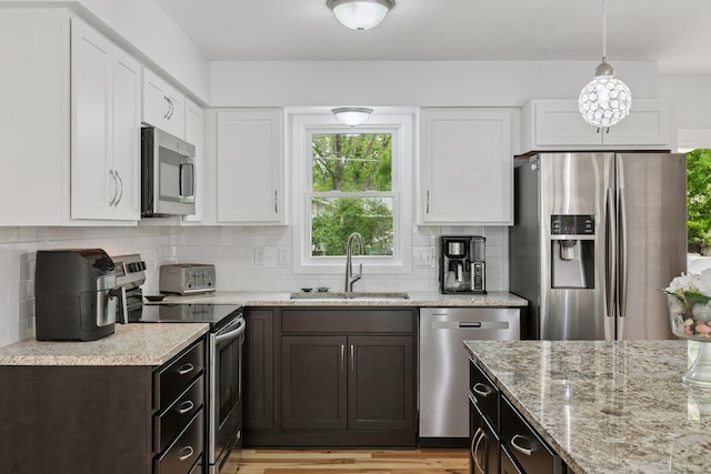 265 107th Ln NW, Coon Rapids, MN 55448 - kitchen featuring appliances with stainless steel finishes, a sink, white cabinets, light stone countertops, and tasteful backsplash