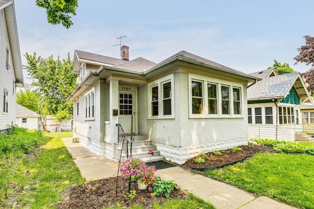 1167 Geranium Ave E, Saint Paul, MN 55106 - view of front of house featuring a chimney, a shingled roof, and stucco siding